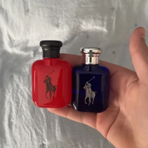 Ralph Lauren Polo parfym duo - Två miniflaskor parfym från Ralph Lauren Polo – en i röd glasflaska med svart kork och en i mörkblå glasflaska med silverkork. Båda har den klassiska polospelaren tryckt på framsidan. Perfekt för dig som gillar stilrena och sportiga dofter.