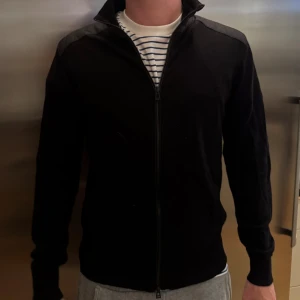 Svart Belstaff cardigan  - Hjälper min bror att sälja hans cardigan från Belstaff. Modellen heter Kelby Zip Cardigan. Använd enstaka gånger, då den inte kommer till användning. I storlek M.   Nypris 2099kr   Tveka inte på att höra av er om ni har frågor!☺️