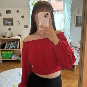 Röd offshoulder blus från H&M Divided - Säljer en röd offshoulder blus från H&M Divided i storlek M men funkar för S också. Toppen har smockad kant upptill och nedtill, croppad passform och långa puffärmar. Materialet är mjukt och lätt, perfekt för att ge en chill och snygg vibe. Framhäver axlarna och har en elastisk midja.❤️❤️