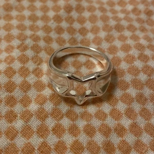 Silvrig ring med stjärnformad öppning - Cool ring i silverfärgad metall med en öppen stjärnformad design i mitten. Ringen har en chunky känsla och passar perfekt för dig som gillar unika detaljer och vill sticka ut lite extra. Snygg att bära ensam eller att kombinera med andra ringar :) Knappt använd. Har dock pyttesmå repor på sig men absolut inget man tänker på 😊