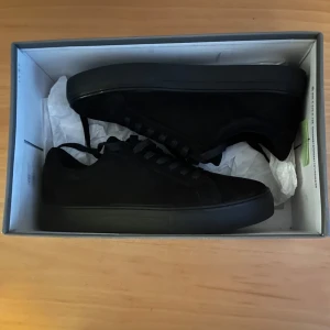 Svarta sneakers från Vagabond (Storlek 40) - Vagabond PAUL 2.0 Helsvarta, STRL 40, helt oanvända sneakers med extra sulor.  Säljer ett par stilrena Vagabond skor i helsvart färg. Skorna är helt oanvända och i perfekt skick de har aldrig använts utomhus. I köpet ingår dessutom extra sulor (vilket är bra då dem är något stora i storleken) vilket gör dem ännu mer bekväma och praktiska.  Denna modell är känd för sin minimalistiska design, höga komfort och tidlösa stil, De helsvarta sneakersen är enkla att matcha med alla typer av outfits.