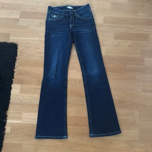Mörkblå bootcut jeans - Snygga mörkblå jeans med bootcut passform och tydliga vita kontrastsömmar. Snygga fickor! Använda fåtal gånger!! Jag är ungefär 1,66/1,67