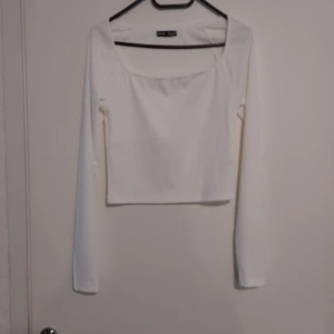 Vit långärmad croppad topp från SHEIN - Säljer en stilren vit långärmad topp från SHEIN i storlek M. Toppen är croppad med fyrkantig ringning och har en clean look som passar till jeans eller kjol. Materialet är mjukt och stretchigt, perfekt för dig som gillar minimalistisk stil.Helt ny.