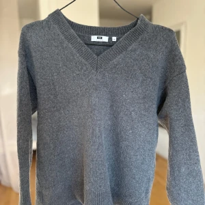 Grå stickad tröja med v-ringning - Mysig grå stickad tröja från WE Studio i storlek XS. Tröjan har en djup v-ringad hals och långa ärmar med ribbade muddar. Perfekt för dig som gillar enkel och stilren design med en loose passform. Materialet är mjukt och passar bra under kyliga dagar.