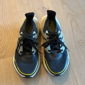 Adidas Ultraboost svarta sneakers - Säljer ett par Adidas Ultraboost sneakers i svart med vita och grå detaljer samt gula accenter. Har använts fåtal gånger. 
