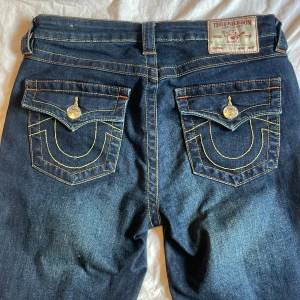 True Religion Becca Bootcut Jeans - Mörkblå bootcut jeans från True Religion, modell Becca mid waist. Väldigt snygga men är tyvärr för stora, används ungefär 2 gånger men har små hål på hälarna men inget som syns när man har på dom.