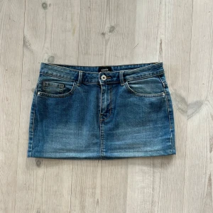 Blå lågmidjad jeanskjol  - Ljusblå lågmidjad jeanskjol från Only i storlek 38. Fint skick. Tvärs över midjan är det 39 cm + stretch och den är 29 cm lång (längs med sidan). Använd gärna köp nu!