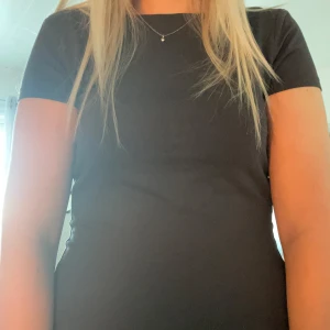 Grå topp med öppen rygg - Säljer en grå topp med tight passform och rund hals. Toppen har korta ärmar och en riktigt snygg öppen rygg som ger en cool vibe. Materialet känns mjukt och stretchigt, perfekt för dig som gillar minimalistisk stil med en twist.