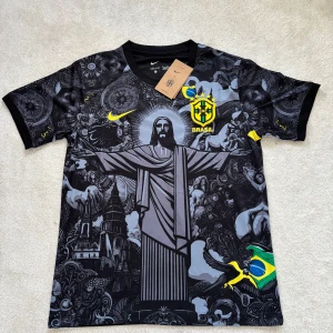 Svart Brasil Nike fotbollströja S - Unik svart Brasilien fotbollströja från Nike med detaljerat grafiskt tryck av Kristusstatyn och brasilianska motiv. Gula och gröna inslag, Brasil-logga på bröstet och ryggen, samt korta ärmar. Tillverkad i lätt och ventilerande polyester, perfekt för match eller träning.
