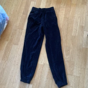 Svarta velourbyxor från C XS - Mysiga svarta velourbyxor från C i storlek XS. Byxorna har resår i midjan med snörning och resår vid bensluten för en chill och skön passform. Perfekta för att hänga hemma eller när du vill vara extra comfy.