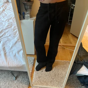 Svarta mjukisbyxor från Kappahl - Svarta mjukisbyxor från Kappahl i storlek S. Byxorna har resår i midjan med snörning och raka ben med lite loose fit. Perfekta för chill dagar och har en enkel, stilren look. Mjukt material som känns skönt mot huden.