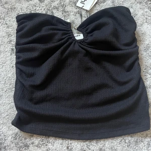 Svart tubtopp med pärldetalj - Helt oanvänd och supersnygg svart tubtopp men pärlderaljer från Bik Bok i storlek S. 