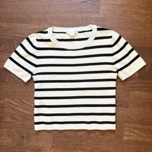 Randig croppad topp från Gina Tricot Young stl.146/152 - Stl.146/152 Superfin croppad topp från Gina Tricot Young i svart och vitt med klassiskt randigt mönster. T-shirten har rund halsringning och korta ärmar. Materialet är mjukt och stretchigt. Nyskick