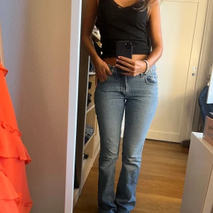 Blå bootcut jeans från Gul och Blå  - Snygga ljusblå jeans från Gul och Blå med klassisk femficksdesign och bootcut-ben. Medelhög midja och raka sömmar ger en clean look. Jeansen är i mjukt denim-material och har metallknappar och detaljer vid fickorna.