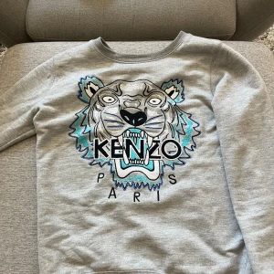 Grå Kenzo tröja med tigertryck - Säljer en grå crewneck från Kenzo i storlek S. Finns 2 jätte små hål i tröjan.
