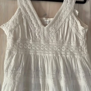 Vit långklänning Corte Hindú med spets - Superfin vit långklänning från Corte Hindú, köpte själv på en fransk söndagsmarknad för 35€. Klänningen har broderade detaljer, spets och volanger som ger en bohemisk vibe. Tillverkad i mjuk bomull, perfekt för varma dagar. Passar dig som gillar romantisk och avslappnad stil.