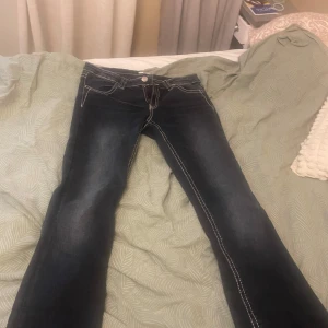 Mörka jeans med broderade bakfickor - Snygga mörkblå lågmidjade jeans från Gina Tricot med kontrastsömmar och broderade detaljer på bakfickorna. Jätte fina boot cut jeans som jag bara använt några gånger. 