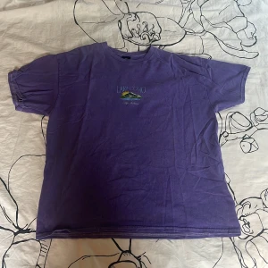 Lila t-shirt från Urban Outfitters - Snygg lila t-shirt från Urban Outfitters med trycket 'Lake Como' och en liten illustration på bröstet. Modellen är klassisk med rund hals och korta ärmar. Materialet är mjuk bomull som känns skönt mot huden. Perfekt för dig som gillar chill och färgglada plagg. Inga defekter. Priset kan diskuteras. 