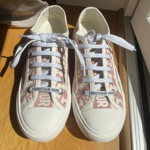 Dior skor  - Super snygga Walk'n'Dior Sneakers från dior i storlek 38 och i super gott skick! Köpt av en tjej på plick för  5000 kr, tyvärr är dessa för små för mig eftersom jag egentligen har 38,5 i storlek :) Har ingen aning om äkthet eftersom inget kvitto medföljde, därav det låga priset. De är mer ljus rosa i verkligheten än på bild. Box medföljer!