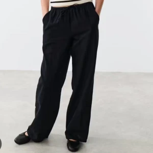 Svarta vida linnebyxor med resår - Snygga svarta linnebyxor med avslappnad passform och resår i midjan. Byxorna har raka, vida ben och sidfickor, perfekta för en chill och stilren look. Lätta och luftiga, passar grymt till sneakers eller ballerinas. Storlek 146-152 