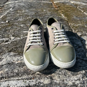 Lanvin Cap-to  - Snygga sneakers från Lanvin i beige mocka med olivgröna lackdetaljer på tå och häl. Skorna har vita snören och en vit sula. Perfekt för dig som gillar stilrena och unika sneakers med en lyxig touch.