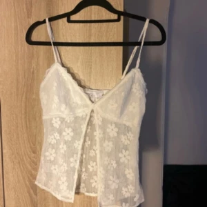 Vit blommig spetslinnetopp från Luvalot - Superfin vit linne-topp från Luvalot med tunna axelband och blommigt spetsmönster. 
