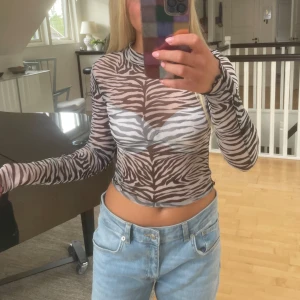 Zebramönstrad mesh topp - Säljer en transparent zebramönstrad mesh topp med lång ärm och tight passform.