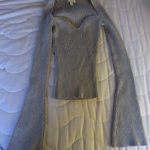 Glittrig silver topp från H&M XS - Supersnygg ribbad topp från H&M i glittrigt silver. Figurnära modell med markerad byst, långa ärmar och stretchigt material. Perfekt för dig som vill sticka ut lite extra! Storlek XS.