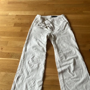 Vita linnebyxor/kostymbyxor med raka ben - Snygga vita linnebyxor/kostymbyxor med raka ben och klassisk passform. Byxorna har diskreta fickor bak. Perfekta för en fräsch och stilren look under varma dagar. Har en liten fläck vid väster ficka men inget som syns 