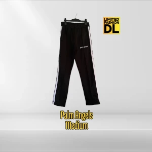 Palm Angels Mjukisbyxor M - Svarta mjukisbyxor från Palm Angels i storlek M. Byxorna har vita ränder längs sidorna, elastisk midja och logga broderad på ena benet. Materialet är en mix av bomull och polyester för skön känsla och streetwear-vibe. Små i storlek 