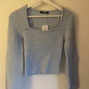 Ljusblå stickad tröja Gina Tricot - Superfin ljusblå stickad tröja från Gina Tricot med fyrkantig ringning och lång ärm. Tröjan är ribbstickad och har en croppad passform som ger en trendig look. Perfekt att styla med jeans eller kjol för en chill vibe.