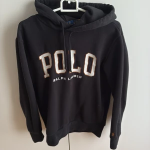 Polo Ralph Lauren hoodie - Svart med vit text, brun brodering runtom texten. Brun logga vid armslutet. Storlek XS. Inga defekter✅. Köpt för ca 2200 kr. Mitt pris:1100 kr. Inget är hugget i sten.