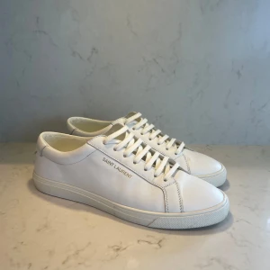 Vita Saint Laurent  - Hola👋Säljer dessa sjukt sjukt snygga Saint Laurent sneakers, perfekta till sommaren för finare stunder och i vardagen• Pris 2100kr• Skick 8,5/10 knapp använda lite crees som knappt syns när de i på, och pytte lite slitna under skon• Storlek 42, 27,5cm• Bättre pris vid snabb affär•kom för fler bilder osv i pm• Caio 👋