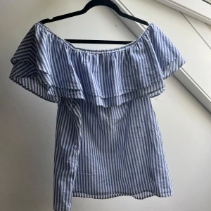 Randig offshoulder topp Gina Tricot - Säljer en blåvit randig offshoulder topp från Gina Tricot i bomull. Toppen har volang runt axlarna och är ärmlös, perfekt för varma dagar. Snygg och luftig modell som ger sommarkänsla direkt. Kom privat för frågor!! Passar S eller M 