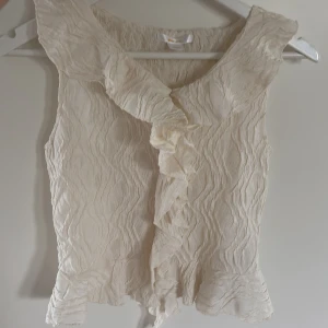 Krämvit volangblus med struktur - Supersöt blus med volanger. Storlek 158/164. Den är i fint skick.