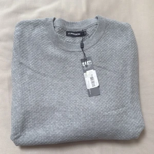 Grå tröja från J.Lindeberg L - Snygg grå stickad tröja från J.Lindeberg med diskret strukturmönster. Helt ny med prislapp! Storlek L 