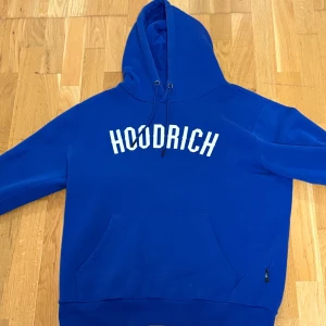 Hoodrich tracksuit - Säljer en blå hoodie från Hoodrich med vit logga framtill och tryck på ryggen. Tröjan har huva med dragsko och en stor magficka. Perfekt för dig som gillar streetwear och vill ha en snygg och bekväm tröja storlek L. Och byxor som är likadana som hoodien. Storlek på byxorna Xl passar även L
