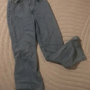 Blå baggy jeans  - Klassiska blå jeans från Levi's med rak passform och normal midja. Jeansen har fem fickor och stängs med dragkedja och knapp. Perfekta för en avslappnad och tidlös stil.