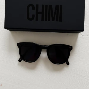CHIMI solglasögon - Snygga svarta solglasögon från CHIMI, modell 001 Berry. Runda linser och klassisk design med två silverprickar på bågen. Inte i toppskick men går fortfarande att använda 😊 vet inte om denna modellen finns att köpa på nätet fortfarande eller om dom uppdaterat just denna modellen men säljer en liknande. Annars stilrena och passar både till kille och tjej, original låda medföljer ej.  Nypris: 1400kr