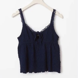 Mörkblå spetsdetaljerad linnetopp - Säljer en mörkblå linnetopp med tunna axelband och spetsdetaljer längs kanterna. Toppen har fina spets detaljer! Och är från gina som är slutsåld just nu!! Toppen passar en mellan M/L och S beroende på size 🍒 väldigt skönt och luftig topp och passar perfekt till ett par jeans!! Skriv gärna om du har några frågor eller är intresserad!!🫶🩷