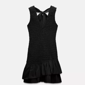 Svart kort klänning med volang - Supersöt svart kortklänning med smockad överdel, v-ringning och volangkant nertill. Klänningen har en snygg knytning i ryggen och är ärmlös, perfekt för en trendig look.