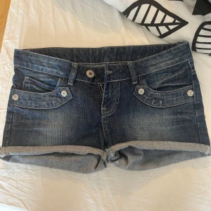 Lågmidjade Blå jeansshorts med uppvik - Snygga blå jeansshorts med klassisk femficksdesign och uppvikta benslut. Midjemåttet är 38cm