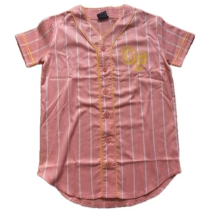 Odd Future basebolltröja - Säljer en rosa basebollinspirerad tröja från Odd Future med vita ränder och gula detaljer. Tröjan har korta ärmar, knappar framtill och tryck med OF-logga fram samt Odd Future-text bak. Perfekt för dig som gillar streetwear och färg.