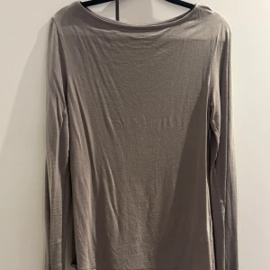 Beige långärmad tröja från 157 - Säljer en enkel och stilren beige långärmad tröja från 157. Tröjan är gjord i mjuk viskosblandning med lite stretch för skön passform. Perfekt att matcha med jeans eller kjol för en clean look.