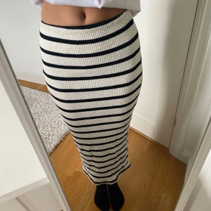 Randig ribbad långkjol.  - Säljer en snygg långkjol med svartvita ränder i ribbstickat material. Den har en liten slits bak som blir en väldigt fin detalj! Säljer den då den inte kommer till användning. 