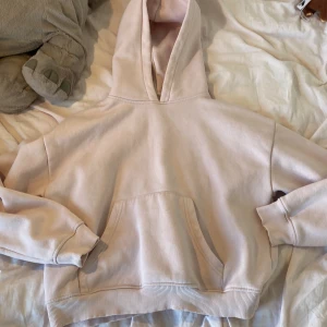 Ljusrosa hoodie med huva - Mysig ljusrosa hoodie med stor huva och magficka. Tröjan har en relaxed passform och ribbade muddar vid ärmslut och nederkant. Perfekt för chill dagar eller när du vill vara extra comfy. 