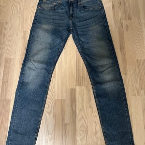 Blå jeans från 157, storlek L - Snygga blåa jeans i storlek L, 32 längd . Passar den med 31, 32 eller 33 i midjan beroende på hur tight man vill de ska sitta. Klassisk femficksmodell med raka ben och diskret slitning på låren och knäna. Jeansen har en mörkblå tvätt och är tillverkade i bomull. Perfekta för en avslappnad och stilren look.