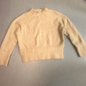 Beige stickad tröja från Zara - Mysig beige stickad tröja från Zara med rund halsringning och breda ribbade muddar vid ärmslut och nederkant. Tröjan har en rak passform och en diskret söm framtill som ger en stilren look. Perfekt för lager-på-lager under kyliga dagar. Skriv för mer frågor och prissänkning💞