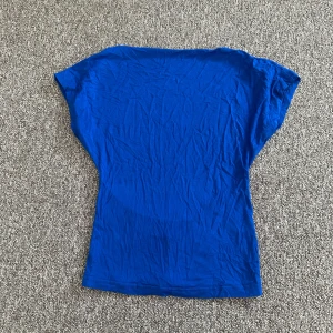 Blå topp med öppen rygg från SHEIN - Snygg blå topp från SHEIN i storlek XS. Modellen har korta ärmar och en öppen rygg. Tunn och mjuk, materialet är bomull. Den är i superfint skick då den inte är använd så mycket därför är den skrynklig. 