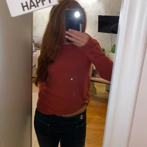 Rostbrun stickad tröja med rund hals - Mysig rostbrun stickad tröja med rund halsringning och långa ärmar. Tröjan har ribbade muddar vid ärmslut och nederkant, vilket ger en snygg och enkel look. Perfekt att matcha med jeans för en chill stil.